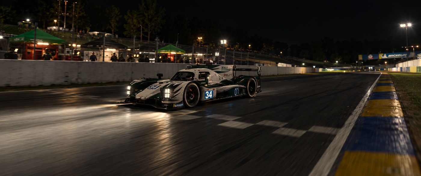 El 34 de noche por la recta de meta de Road Atlanta, junto al muro del pit lane y con la pasarela de Michelin al fondo.